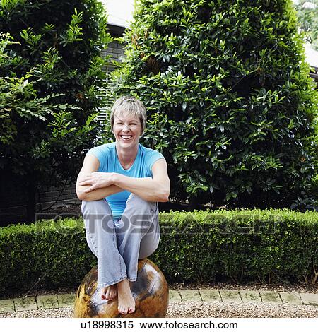 Stock Photography - Mature woman sitting on a rock. Fotosearch
