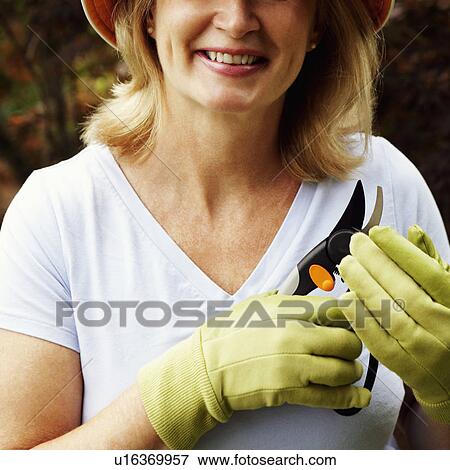 Stock Photo - Mid section view of a mature woman holding a pair of pruning shears. Fotosearch