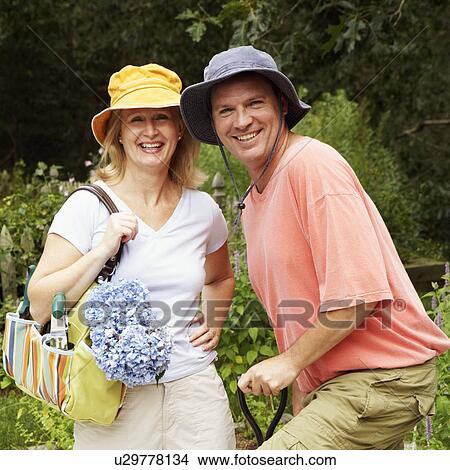 Portrait of a mature couple standing together in a garden and smiling View Large Photo Image Picture - Portrait of a mature couple standing together in a garden and smiling. Fotosearch