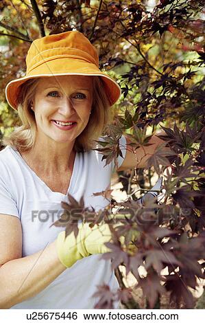 Stock Photograph - Portrait of a mature woman gardening and smiling. Fotosearch