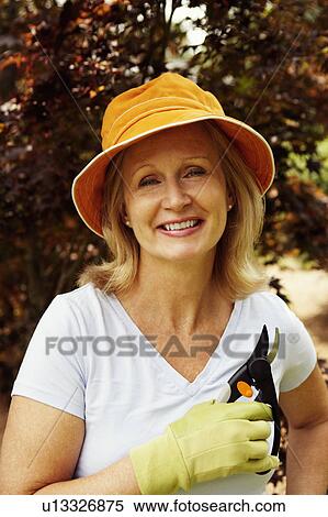 Stock Photography - Portrait of a mature woman holding a pair of pruning shears and smiling. Fotosearch