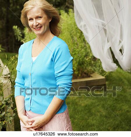 Stock Photograph - Portrait of a mature woman standing and smiling. Fotosearch