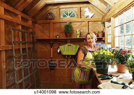 Stock Photo - Portrait of a mature woman standing near potted plants. Fotosearch