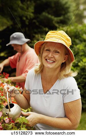 Portrait of a mature woman watering plants and smiling View Large Photo Image Stock Image - Portrait of a mature woman watering plants and smiling. Fotosearch
