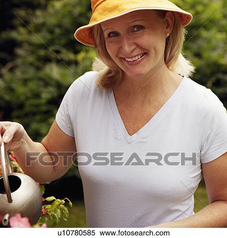 Portrait of a mature woman watering plants and smiling View Large Photo Image Stock Photography - Portrait of a mature woman watering plants and smiling. Fotosearch