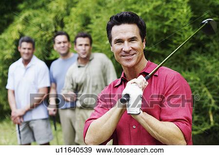 Stock Photo - Mature man holding a golf club with his friends standing behind him. Fotosearch