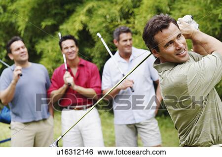 Mature man swinging a golf club with his friends standing behind him View Large Photo Image Stock Photograph - Mature man swinging a golf club with his friends standing behind him. Fotosearch