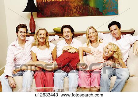 Stock Image - Portrait of a group of people sitting together on a couch. Fotosearch