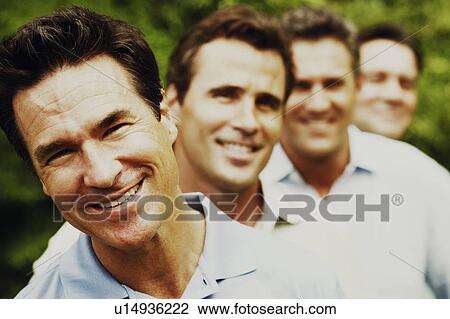 Stock Image - Portrait of a mature man smiling with his friends in the background. Fotosearch