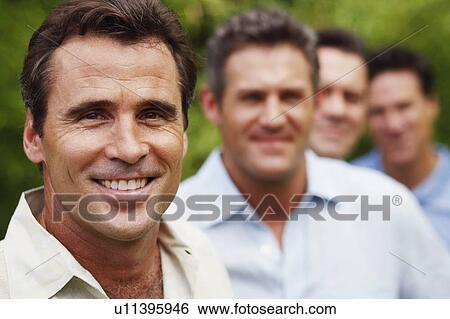 Portrait of a mature man smiling with his friends in the background View Large Photo Image Stock Photograph - Portrait of a mature man smiling with his friends in the background. Fotosearch