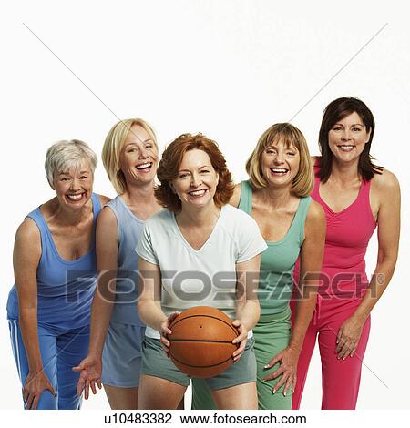 Stock Image - Portrait of a mature woman holding a basketball with her four friends standing behind her. Fotosearch