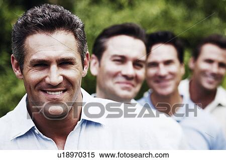 Stock Photography - Portrait of a mid adult man smiling with his friends in the background. Fotosearch