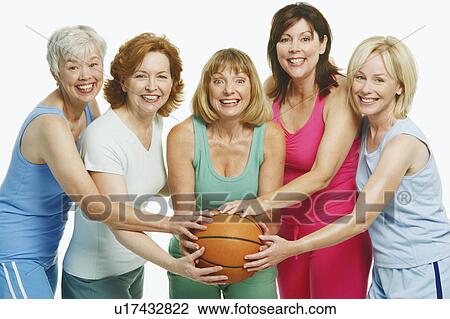 Stock Image - Portrait of five mature women holding a basketball and smiling. Fotosearch