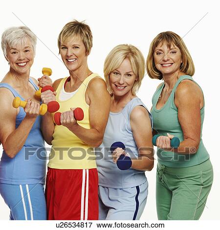 Stock Photo - Portrait of four mature women holding dumbbells and smiling. Fotosearch