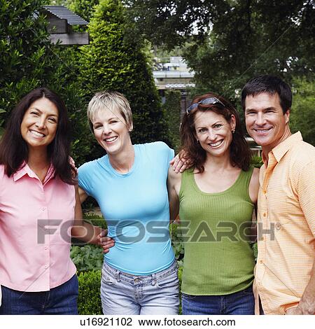 Stock Image - Portrait of three mature women and a mature man standing together and smiling. Fotosearch