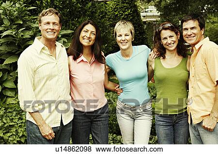 Stock Photo - Portrait of three mature women and two mature men standing together and smiling. Fotosearch
