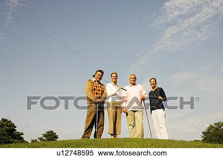 Stock Photography - Portrait of two couples standing on a golf course. Fotosearch