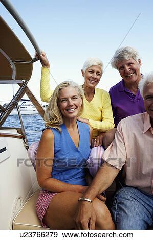 Stock Photo - Portrait of two mature couples sitting in a boat and smiling together. Fotosearch