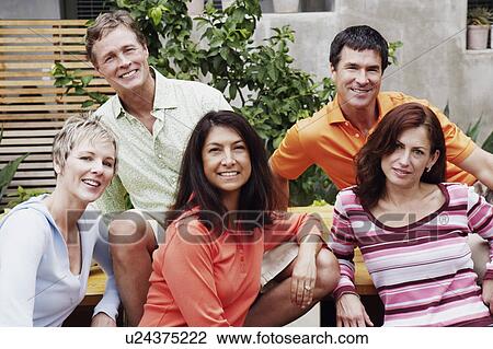 Stock Image - Portrait of two mature men and three mature women sitting together. Fotosearch