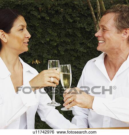Stock Photograph - Close-up of a mature couple toasting with champagne flutes. Fotosearch