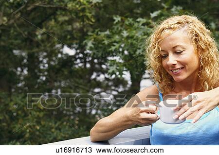 Close-up of a mature woman holding a cup of tea and smiling View Large Photo Image Stock Image - Close-up of a mature woman holding a cup of tea and smiling. Fotosearch