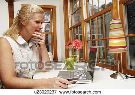 Close-up of a mature woman shopping online View Large Photo Image Stock Photo - Close-up of a mature woman shopping online. Fotosearch