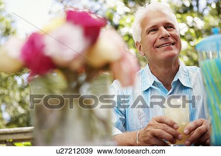 Stock Photo - Mature man holding a glass of juice and smiling. Fotosearch