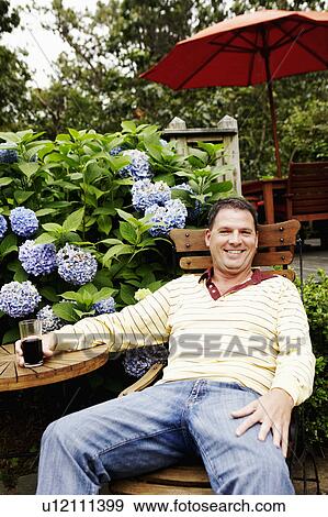 Portrait of a mature man holding a glass and sitting on a chair View Large Photo Image Stock Photo - Portrait of a mature man holding a glass and sitting on a chair. Fotosearch