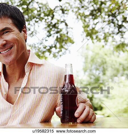 Portrait of a mature man holding a bottle of red wine and smiling View Large Photo Image Stock Photography - Portrait of a mature man holding a bottle of red wine and smiling. Fotosearch