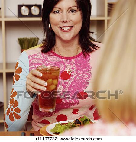 Portrait of a mature woman holding a glass of cocktail with her friend and smiling View Large Photo Image Stock Image - Portrait of a mature woman holding a glass of cocktail with her friend and smiling. Fotosearch