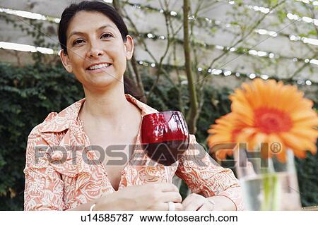 Portrait of a mature woman holding a glass of wine and smiling View Large Photo Image Stock Photo - Portrait of a mature woman holding a glass of wine and smiling. Fotosearch