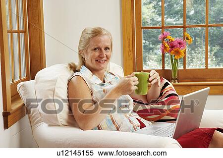 Stock Photography - Portrait of a mature woman holding a coffee cup and smiling. Fotosearch