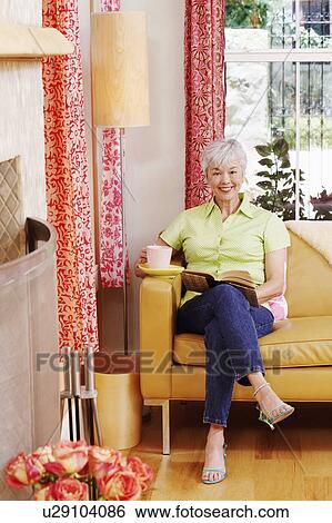 Portrait of a senior woman sitting on a couch with a book View Large Photo Image Stock Photograph - Portrait of a senior woman sitting on a couch with a book. Fotosearch