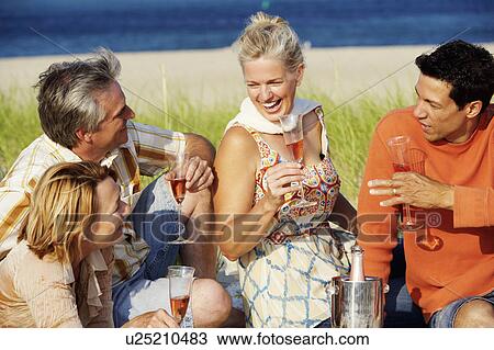 Two mature couples sitting on the beach and holding champagne flutes View Large Photo Image Stock Image - Two mature couples sitting on the beach and holding champagne flutes. Fotosearch