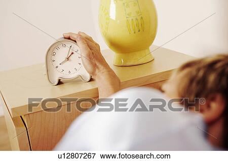 Stock Photo - Close-up of a woman reaching for an alarm clock. Fotosearch
