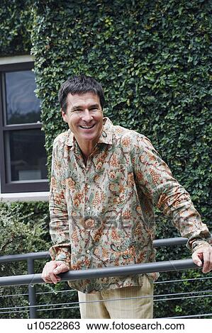 Mature man standing near a railing and smiling View Large Photo Image Stock Image - Mature man standing near a railing and smiling. Fotosearch