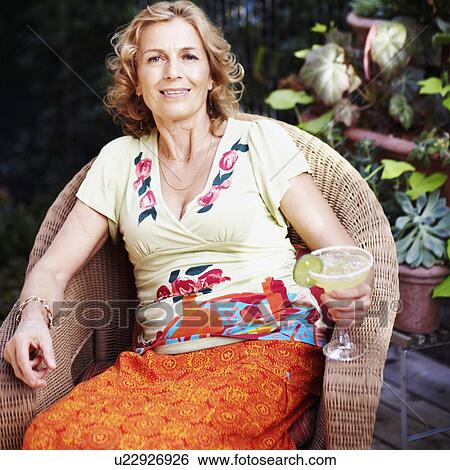 Stock Photograph - Portrait of a mature woman and holding a glass of lemonade and smiling. Fotosearch