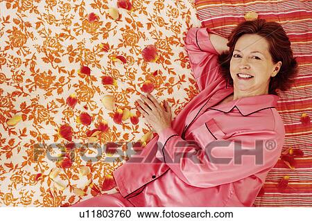 Portrait of a mature woman lying in bed and smiling View Large Photo Image Stock Image - Portrait of a mature woman lying in bed and smiling. Fotosearch