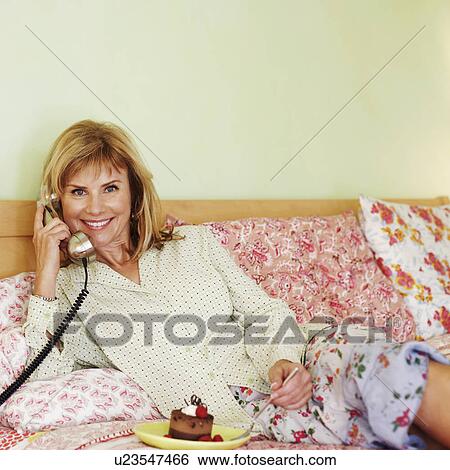 Portrait of a mature woman lying on the bed and talking on the telephone View Large Photo Image Stock Photograph - Portrait of a mature woman lying on the bed and talking on the telephone. Fotosearch