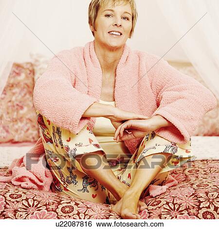 Portrait of a mature woman sitting on the bed View Large Photo Image Stock Photograph - Portrait of a mature woman sitting on the bed. Fotosearch
