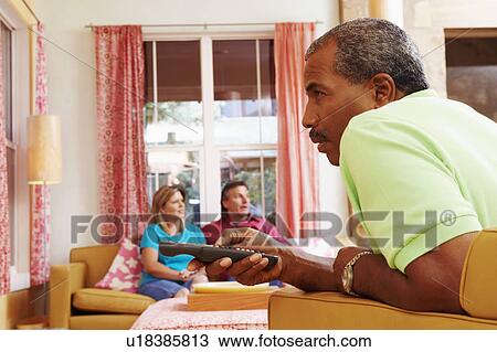 Side profile of a mature man operating a remote control with a mature couple sitting beside him View Large Photo Image Stock Image - Side profile of a mature man operating a remote control with a mature couple sitting beside him. Fotosearch