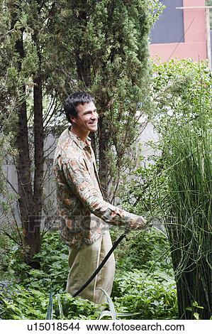 Side profile of a mature man watering plants in the back yard View Large Photo Image Picture - Side profile of a mature man watering plants in the back yard. Fotosearch