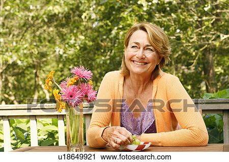 Close-up of a mature woman smiling at the table View Large Photo Image Stock Image - Close-up of a mature woman smiling at the table. Fotosearch