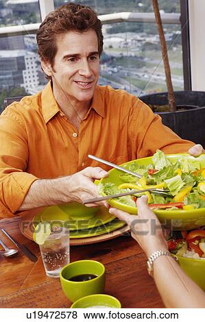 Stock Photo - Mature man giving a plate of salad. Fotosearch