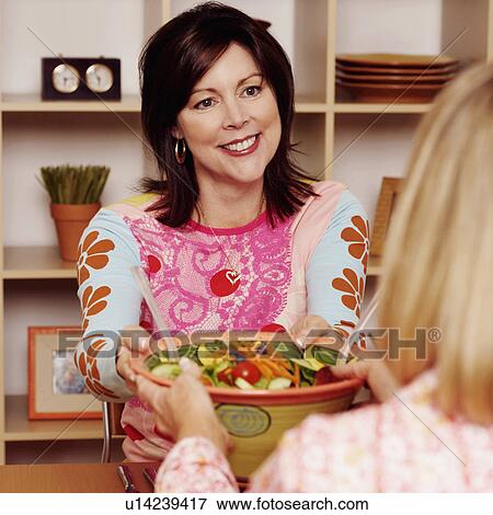 Mature woman giving a bowl of salad to her friend and smiling View Large Photo Image Stock Photo - Mature woman giving a bowl of salad to her friend and smiling. Fotosearch