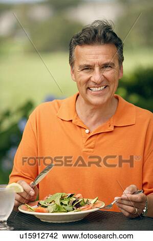 Portrait of a mature man sitting at the table with a plate of vegetable salad in front of him View Large Photo Image Stock Image - Portrait of a mature man sitting at the table with a plate of vegetable salad in front of him. Fotosearch