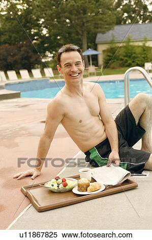 Stock Photography - Portrait of a mature man smiling and sitting at the poolside. Fotosearch