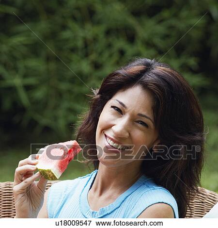 Portrait of a mature woman holding a slice of watermelon and smiling View Large Photo Image Stock Photo - Portrait of a mature woman holding a slice of watermelon and smiling. Fotosearch