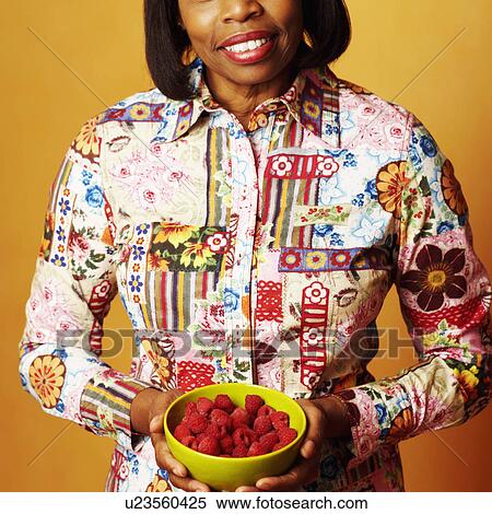 Stock Photography - Portrait of a mature woman holding a bowl of raspberries. Fotosearch