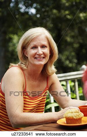 Portrait of a mature woman sitting at the table and smiling View Large Photo Image Stock Image - Portrait of a mature woman sitting at the table and smiling. Fotosearch